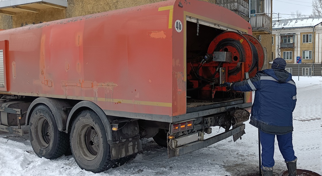 Каналопромывочная машина и работник прочищают засор в канализационной системе в Воркуте